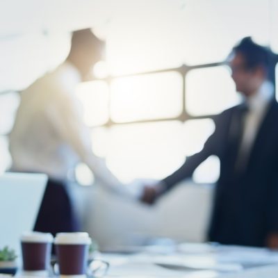 Blurred shot of two businessmen shaking hands in an office