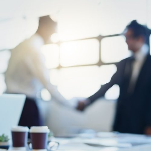 Blurred shot of two businessmen shaking hands in an office